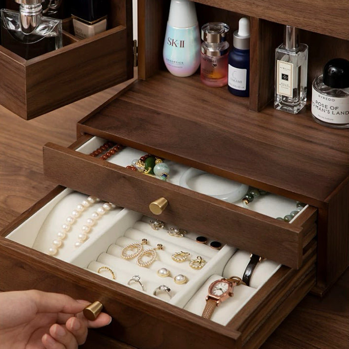 Wooden jewelry box with open drawer displaying jewelry, surrounded by skincare products.
