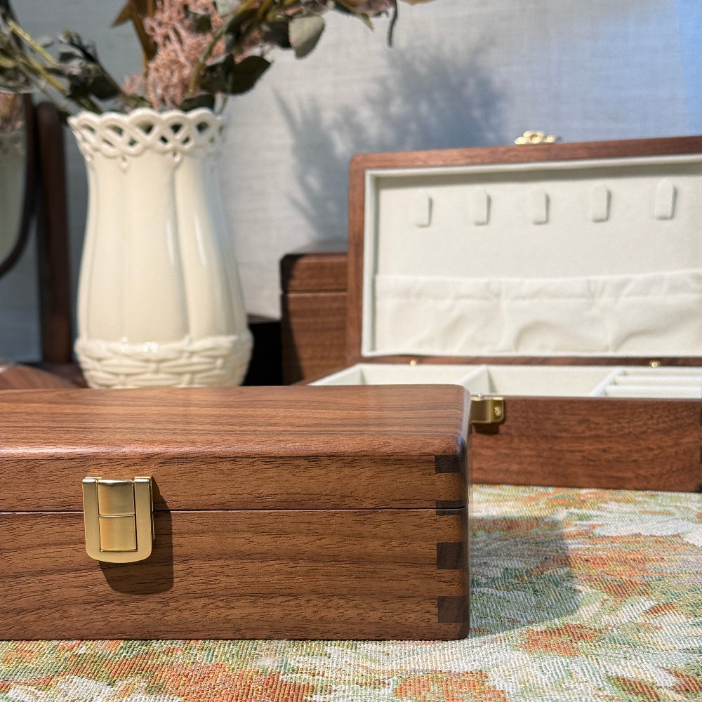 Wooden jewelry box with a gold clasp on a floral-patterned surface